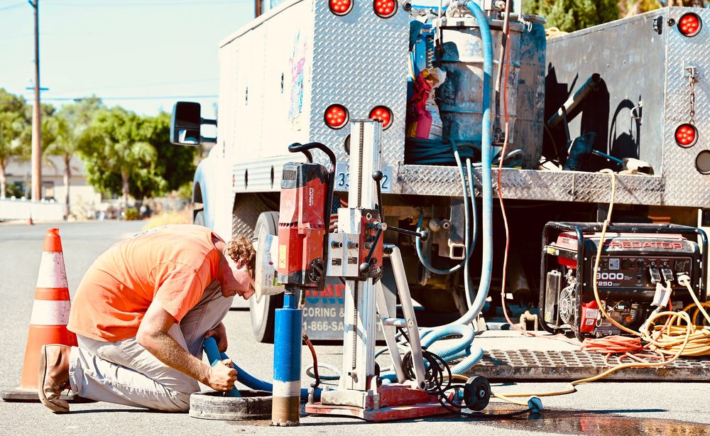 Operator core drilling pavement beside a United service truck