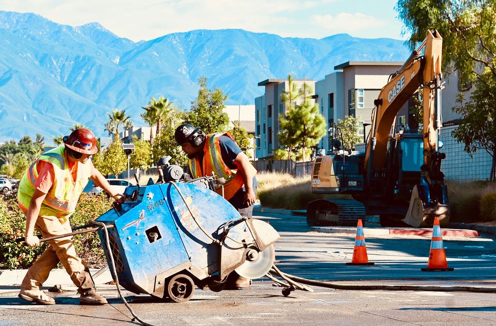 Two operators flat-sawing a street with mountains behind the job
