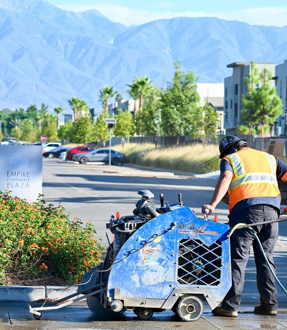 Operator flat-sawing a curb with mountains behind the job site