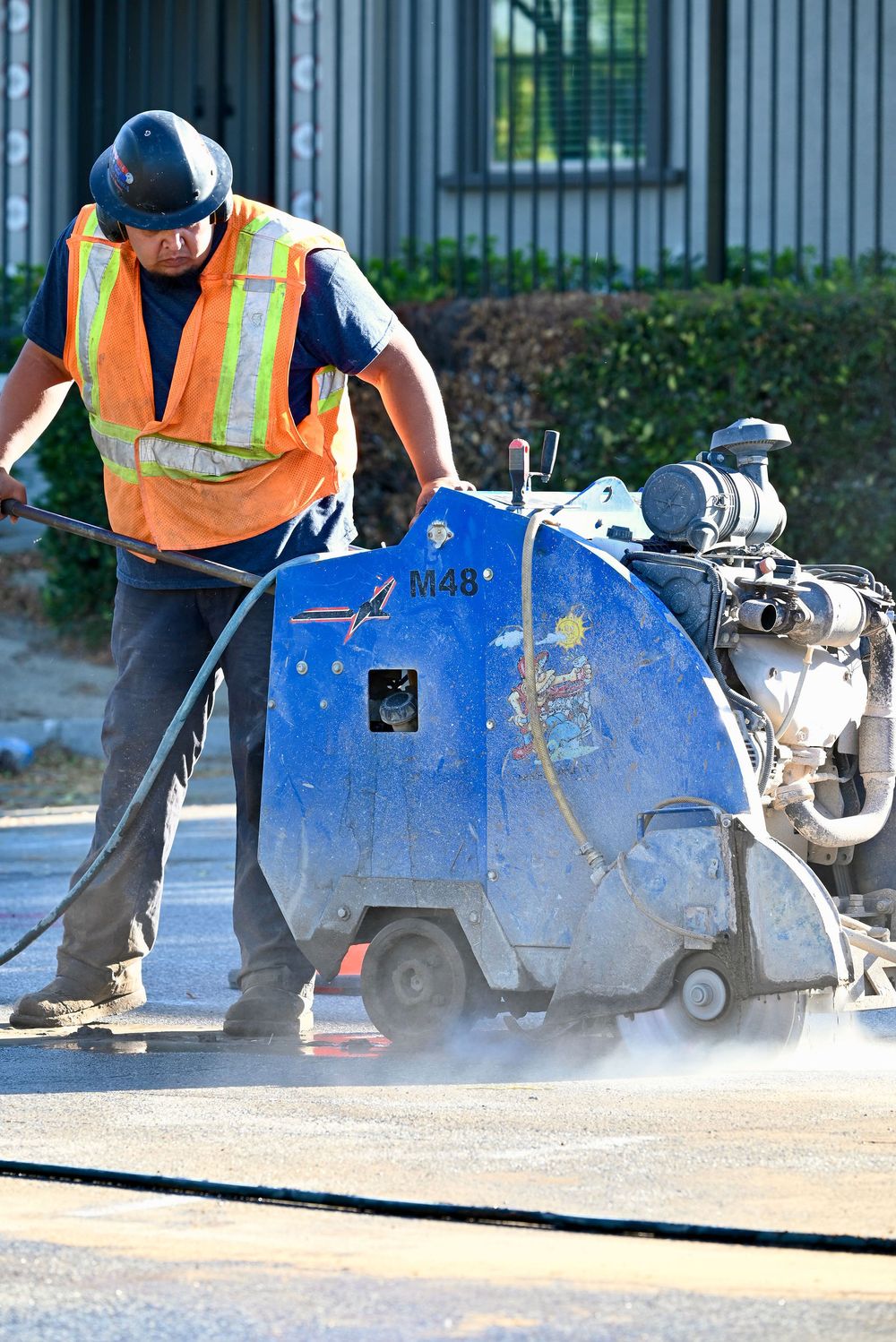 Operator pushing a walk-behind flat saw through pavement
