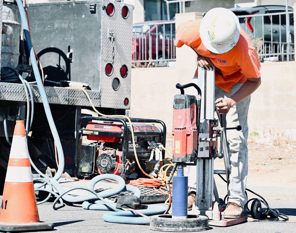 Operator running a core drill beside a generator and service truck