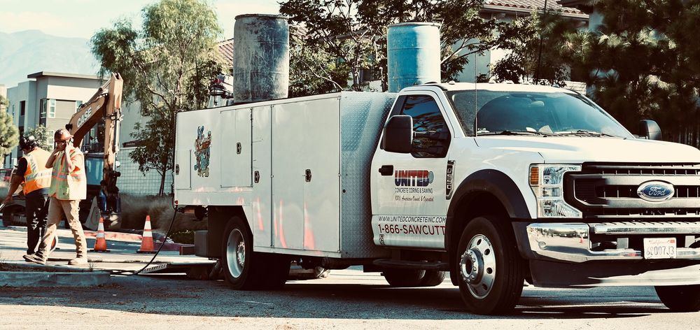 United service truck on a street job with crew members and an excavator nearby