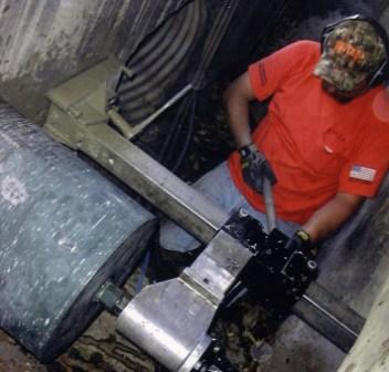Operator core drilling inside a concrete manhole