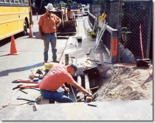 Crew core drilling beside a fenced opening on the 91 freeway bridge job